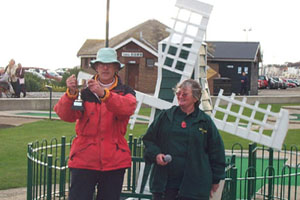 Tim Davies holding trophy aloft in front of the windmill.