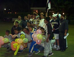 Photo of the top three players with officials and lots of balloons.